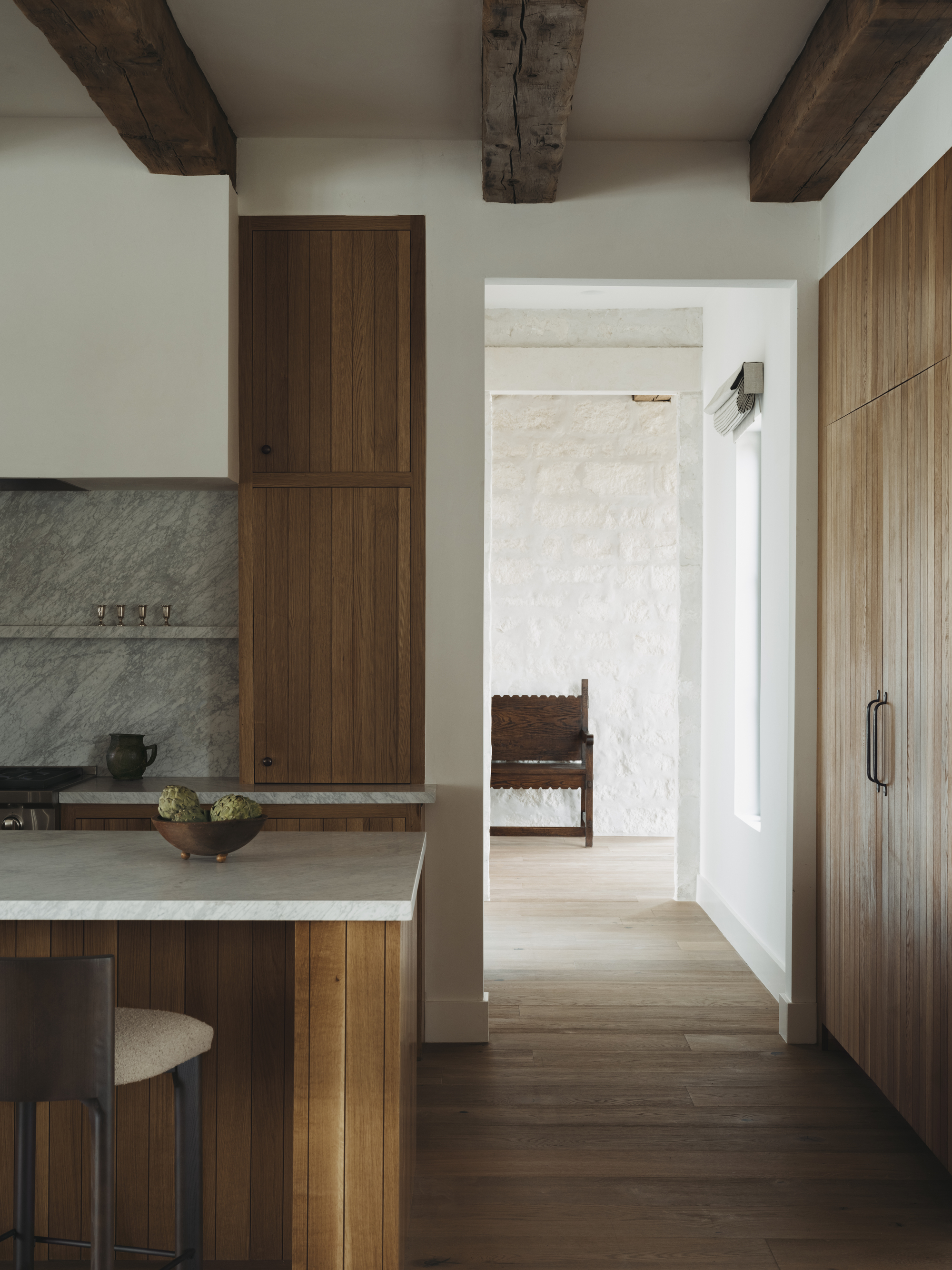 Image of a white kitchen with natural wood paneling on the kitchen island, cabinetry, and walls.