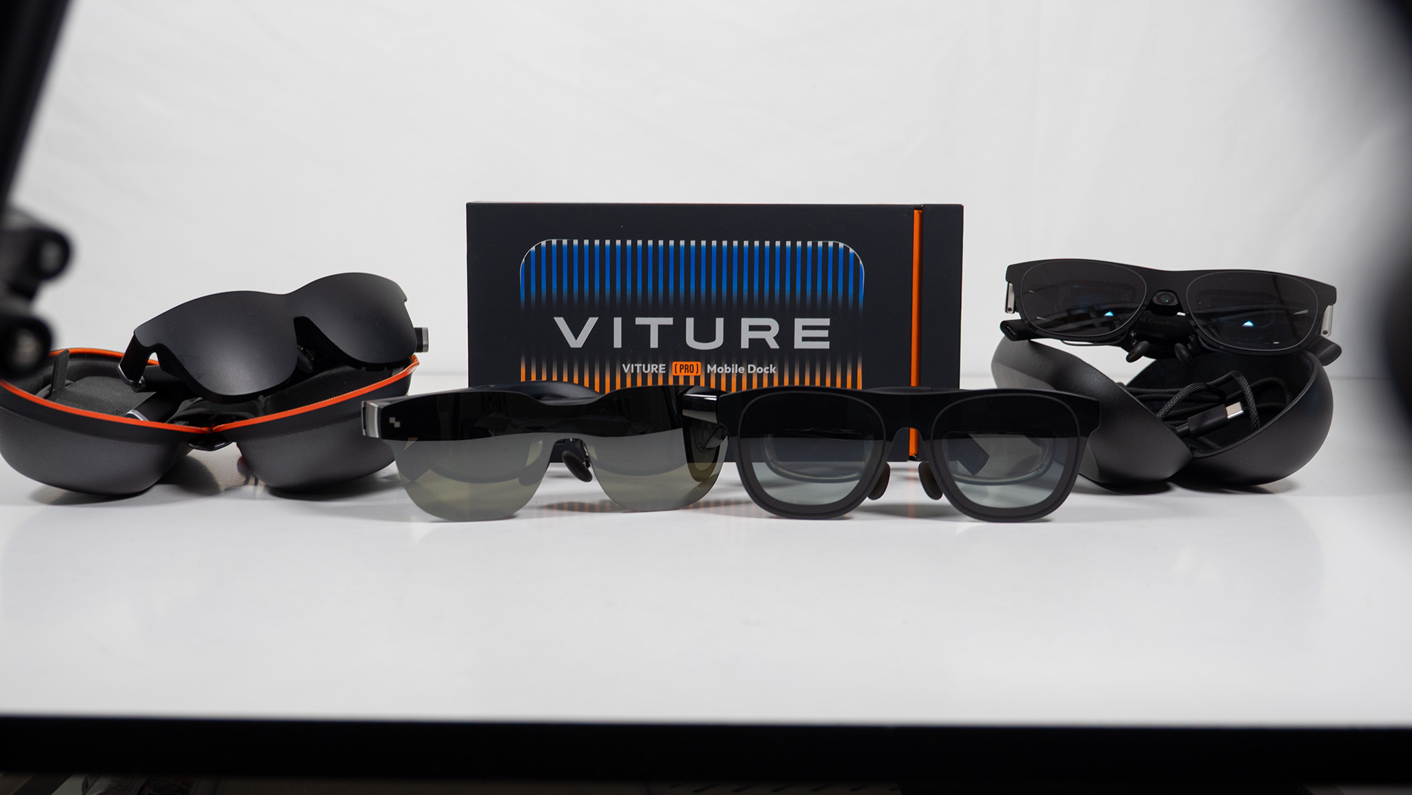 The Viture One Mobile Dock surrounded by several pairs of smart display glasses