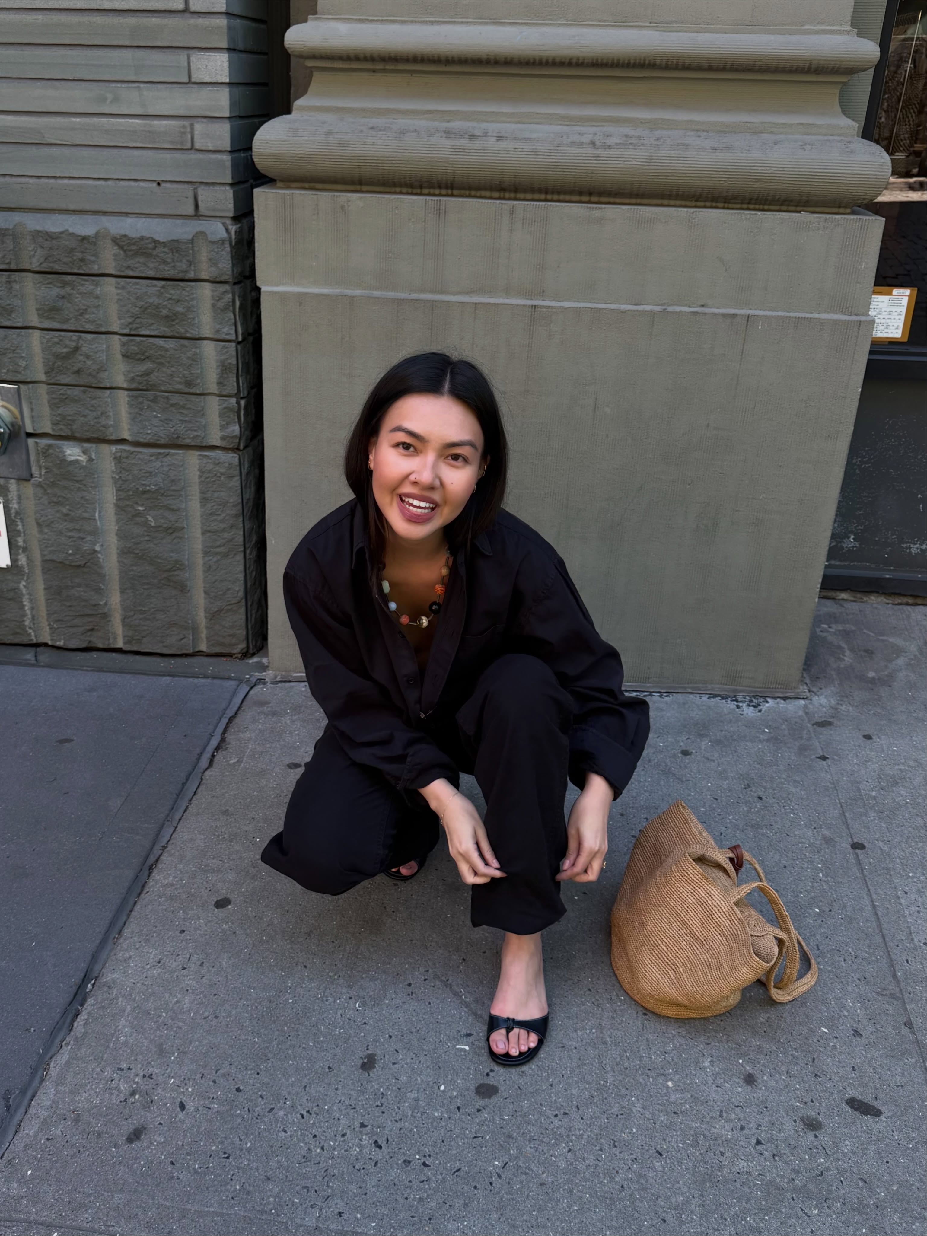 Mimi wears all black outfit, black peep toe sandals and a basket bag
