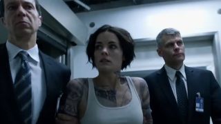 Jaimie Alexander being taken somewhere by men in suits in Blindspot