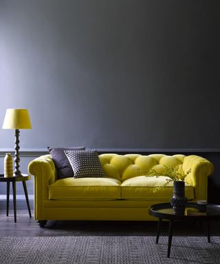 Dramatic contemporary living room with dark charcoal walls and flooring, and zesty citron button-back, velvet sofa.