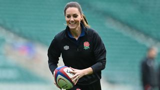 Kate Middleton smiling and laughing holding a rugby ball and running