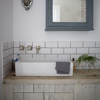 bathroom with white wall wash basin wooden counter and taps