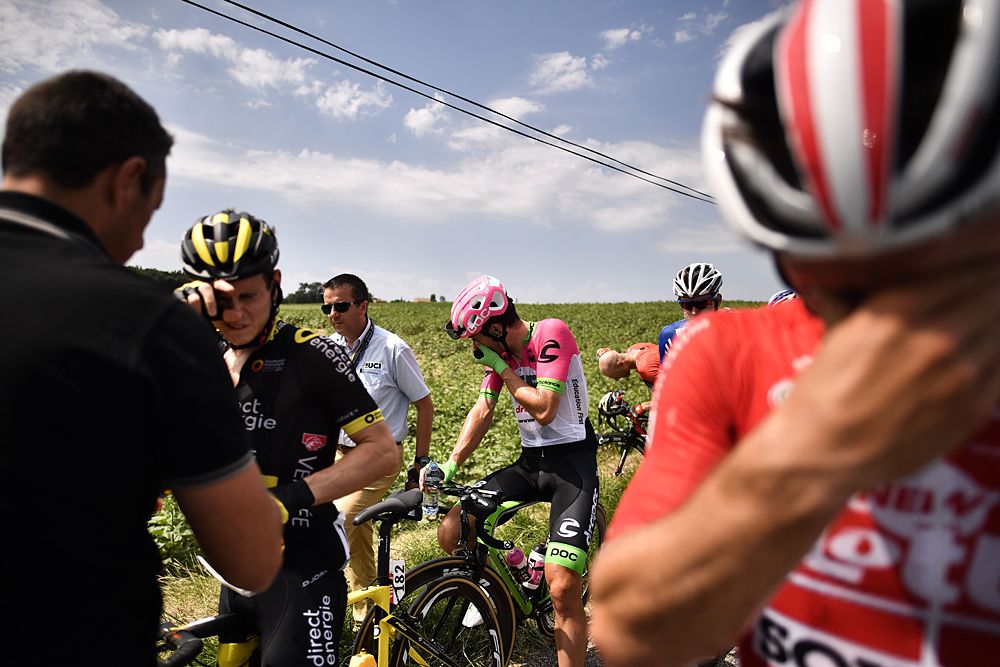 Riders react after riding through tear gas during a farmers' protest who attempted to block the stage's route