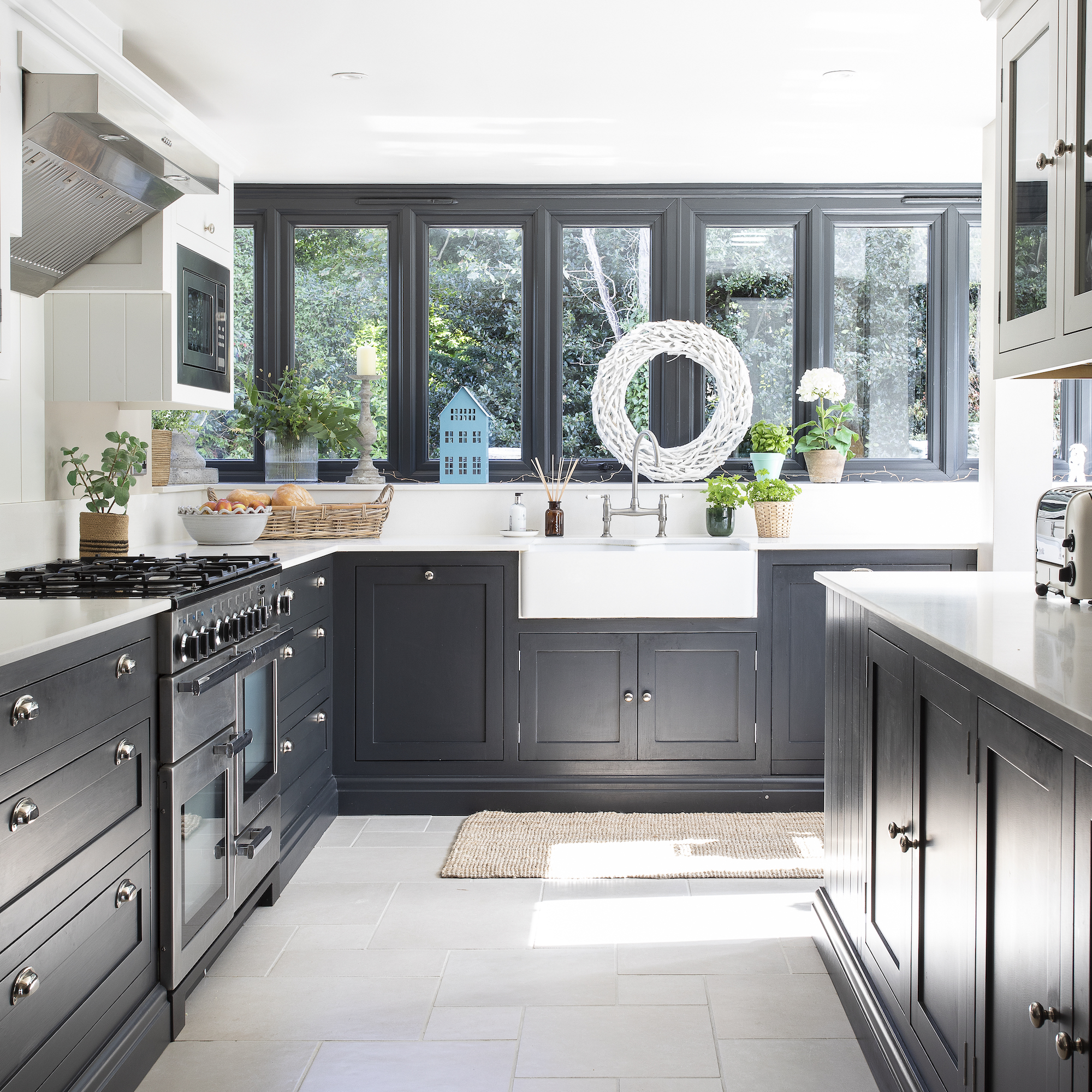 kitchen with dark grey painted cabinets, white bulter sink and stone floor