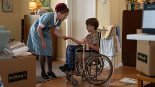 Shelagh wearing her nurses uniform as she checks Andrew's bandaged hand as he sits in his wheelchair