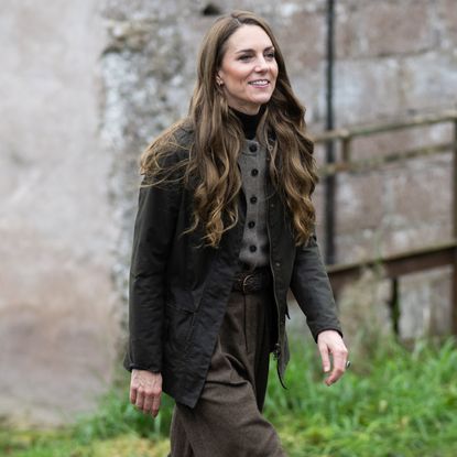 Princess Kate wearing a fall jacket walking in front of a stone building