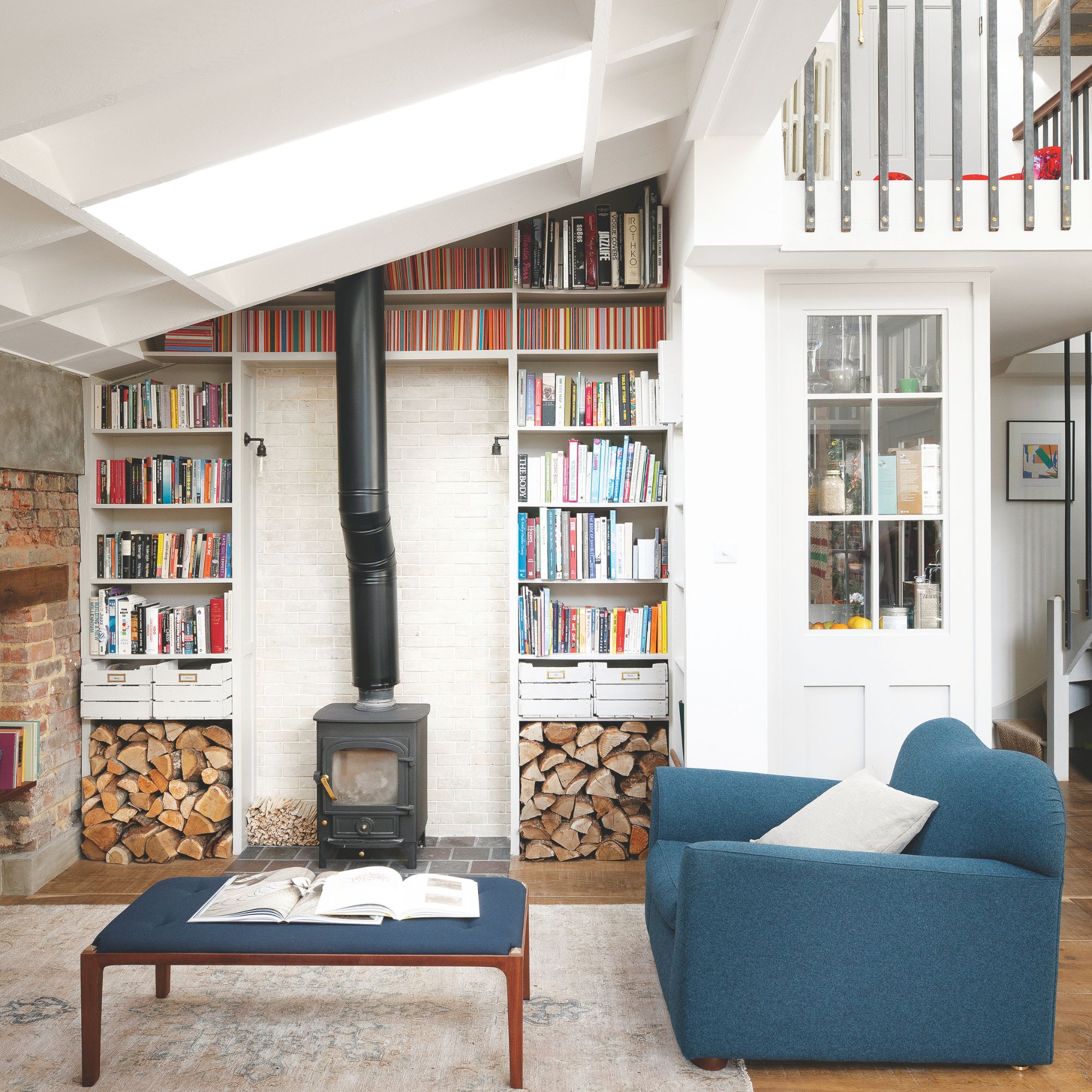 Living room with a log burner and bookshelves around it, with a blue accent chair and matching coffee table in front of it