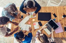 overhead view on young business people around wooden desk