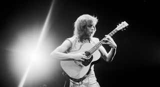 A black-and-white image of Steve Howe fretting a complex chord on his Martin acoustic, onstage with Yes in 1980.