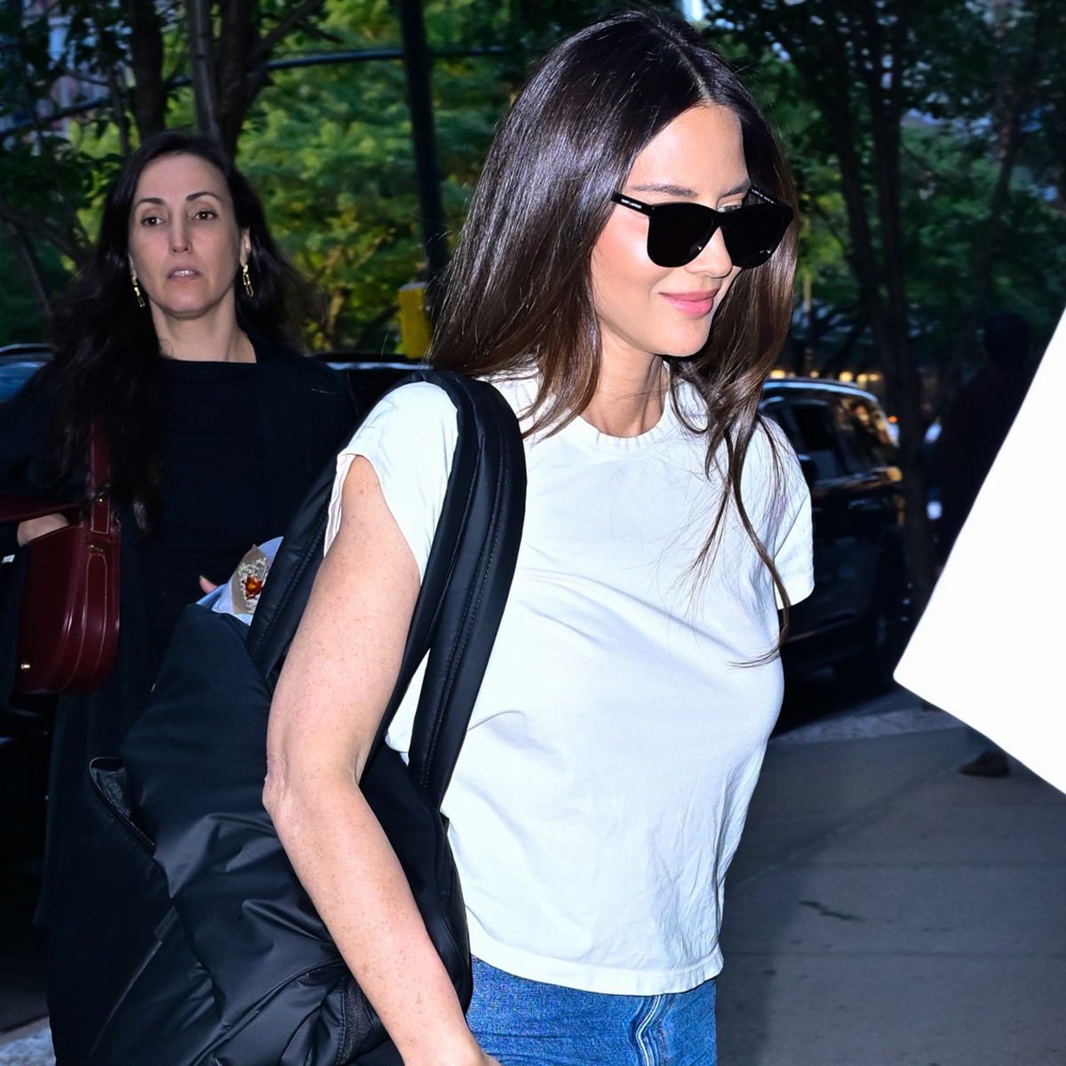 olivia munn wears a white t-shirt, sunglasses, and jeans.
