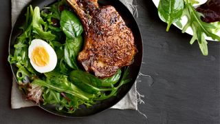 Chops and boiled eggs sitting on plate of spinach