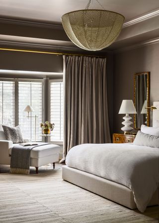 bedroom with taupe colorscheme and double bed with chaise armchair and statement ceiling light