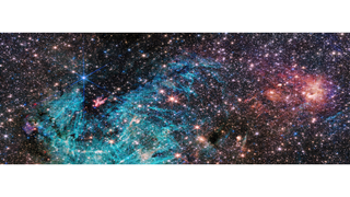 A panoramic image of space, with some pink and blue splotches over the dark background and a huge amount of stars speckled over the entire area.