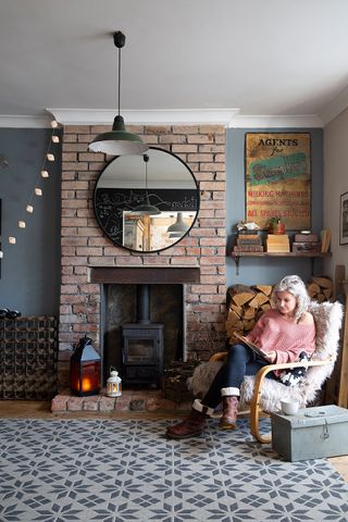 Exposed brick fireplace with woodburning stove and an armchair in front of it