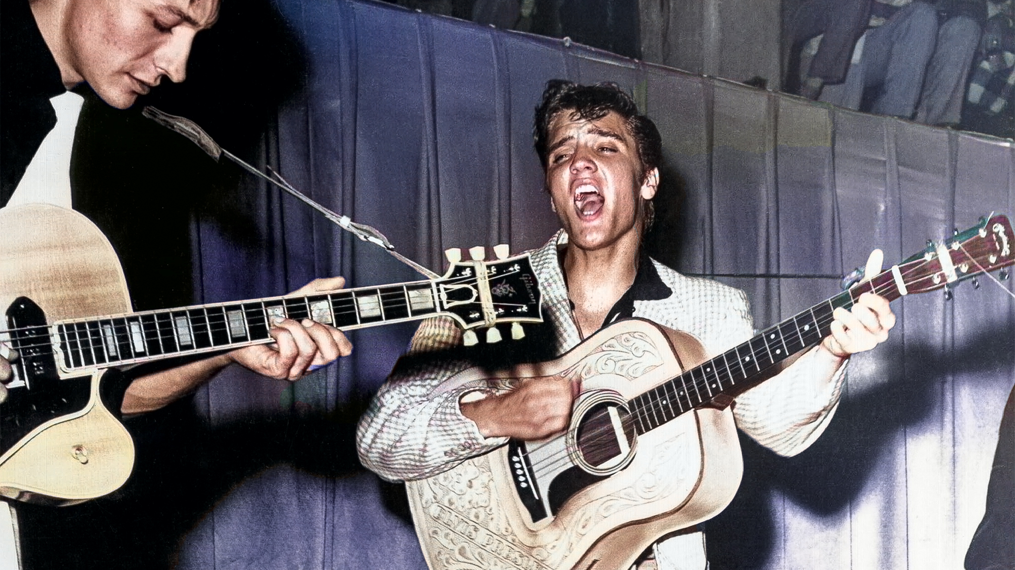 Elvis Presley performs on stage with his brand new Martin D-28 acoustic guitar and Scotty Moore on the left on July 31, 1955 at Fort Homer Hesterly Armory in Tampa, Florida. 