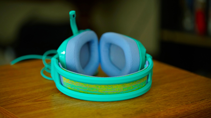 Logitech G335 on a wooden table in front of a bookshelf, showcasing its headband