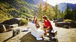 best camping coolers: couple with a big camping cooler box in the backcountry