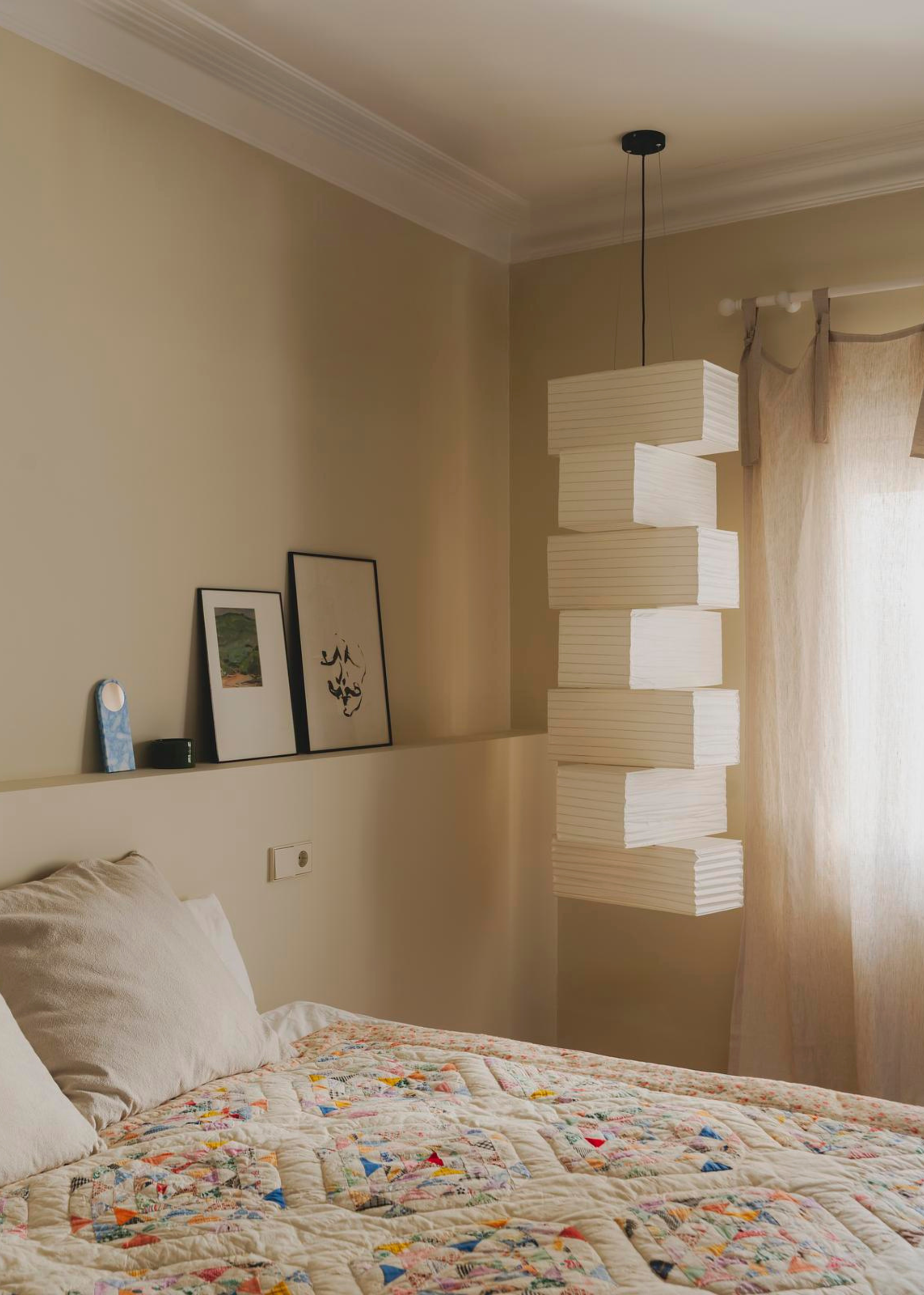 A bright bedroom with a hanging paper lantern beside the bed