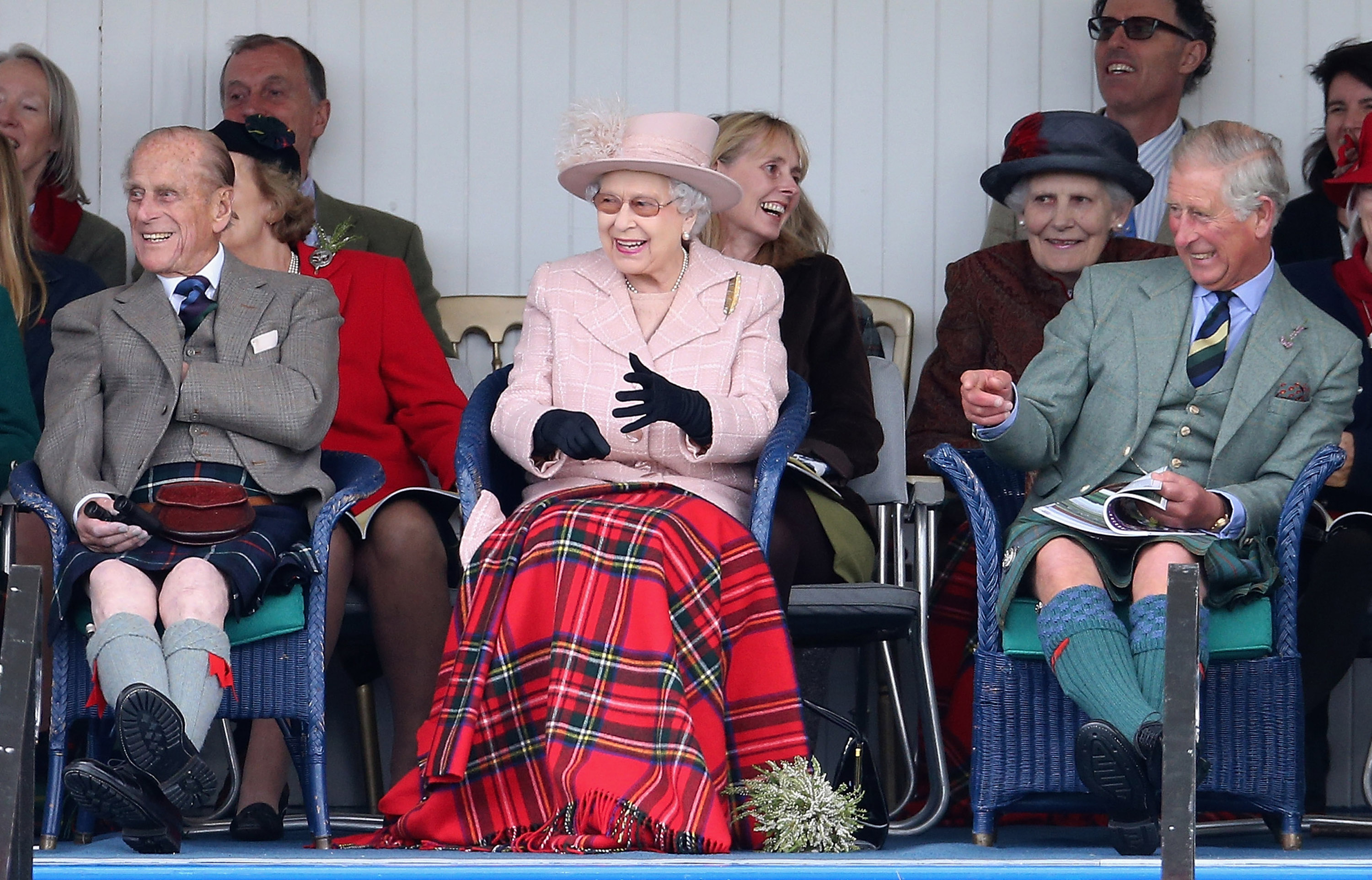 Prince Philip, Queen Elizabeth and Prince Charles wearing kilts and laughing in Scotland