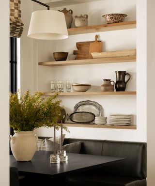 Neutral rustic shelves with tableware and black table and leather seating