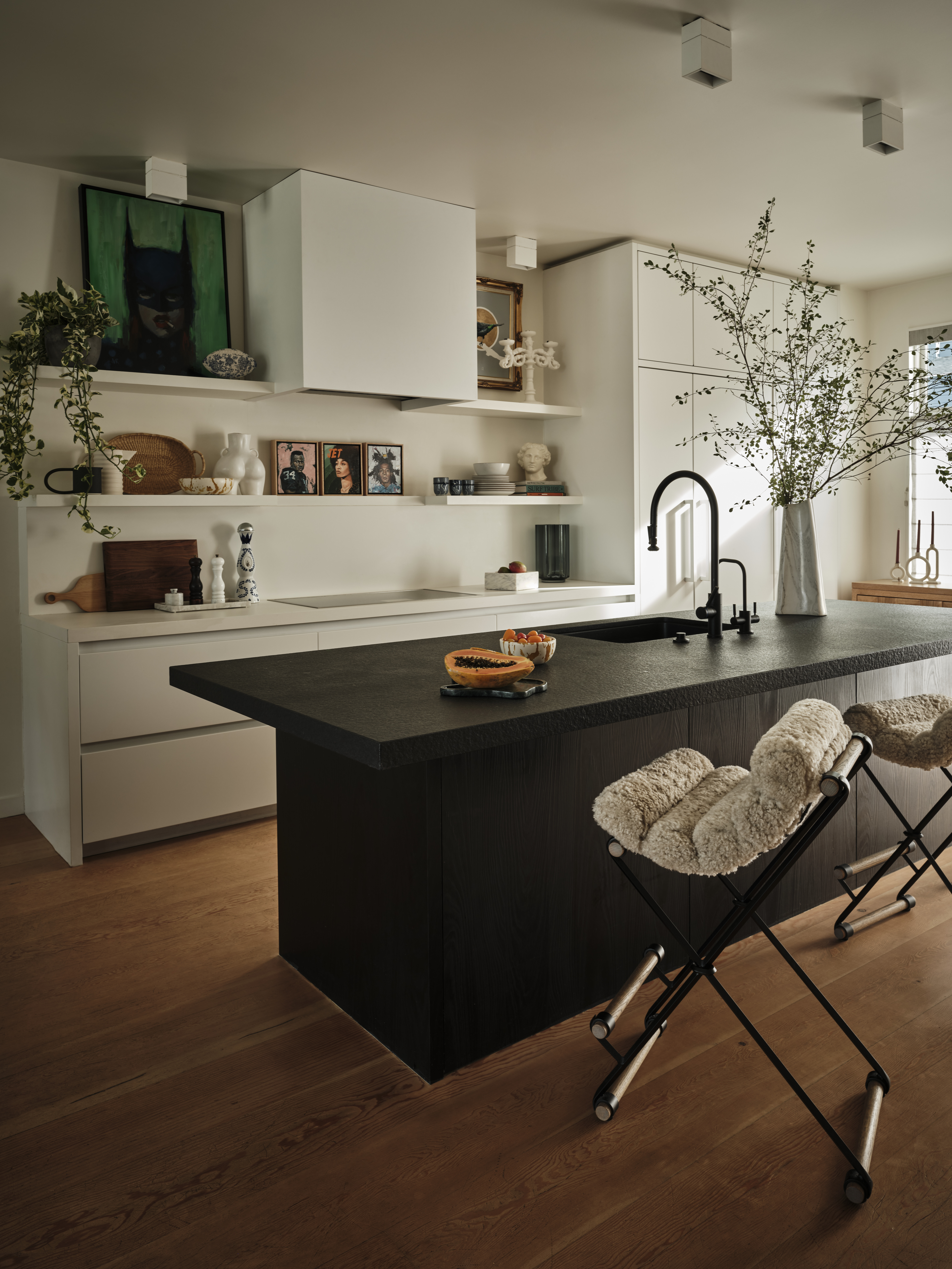 A kitchen painted in cream walls, with a black kitchen island in the middle