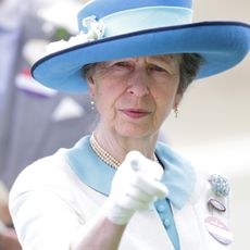 Princess Anne wears a turquoise and white outfit and points at the camera, and in another photos she wears a green tweed jacket and a navy hat