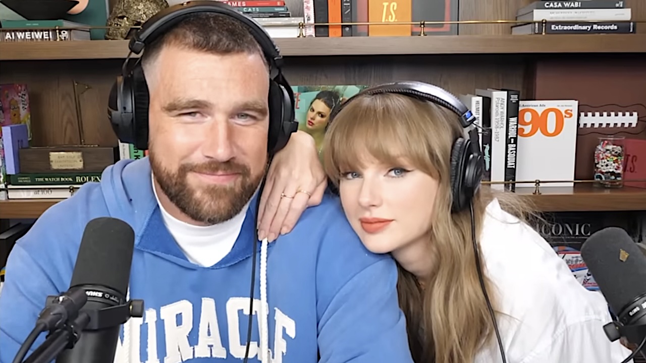 Taylor Swift leaning on Travis Kelce while they both wear headphones on the New Heights podcast. 