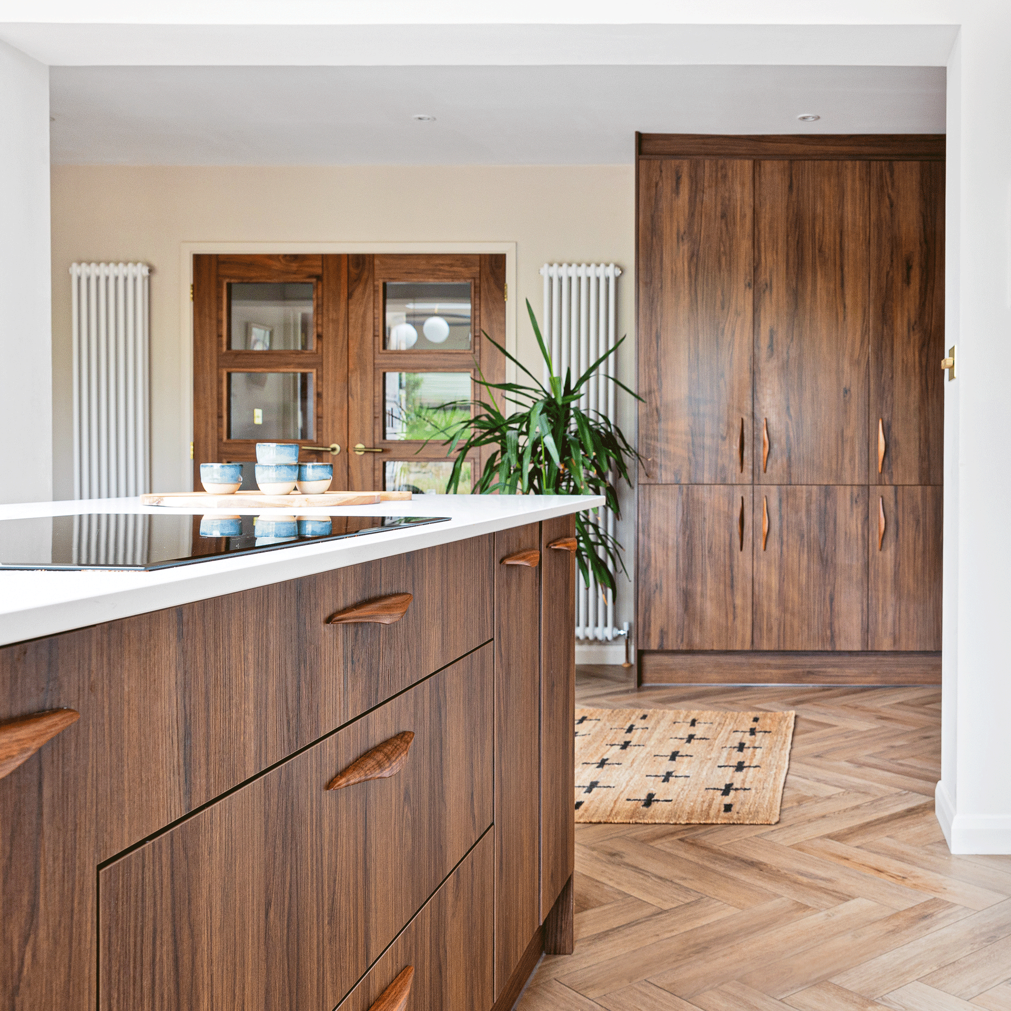 a dark wood kitchen with herringbone flooring white walls and white countertops