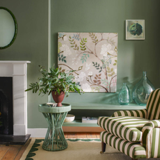 Soft green walled living room with green furniture and a green striped armchair.