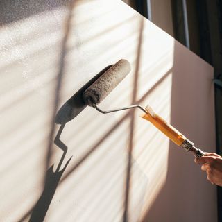 Someone using a paint roller to paint walls