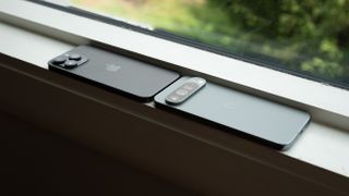 An Apple iPhone 14 Pro Max next to a Google Pixel 9 Pro XL on a windowsill