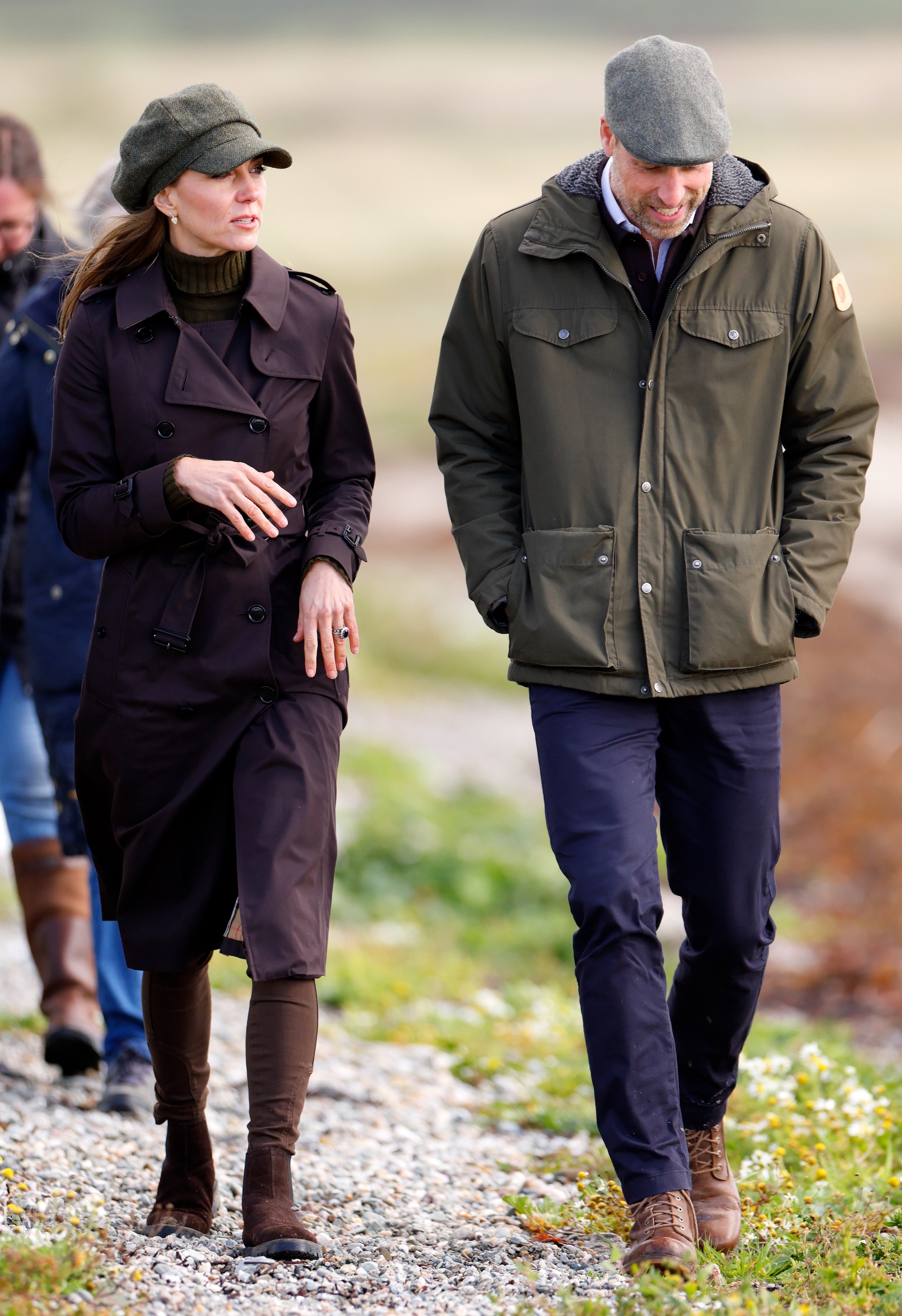 Prince William walking next to Princess Kate in a flat cap and green coat