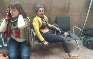 Two women sit in shock moments after a suicide bomb exploded at Zaventem airport in Brussels in March