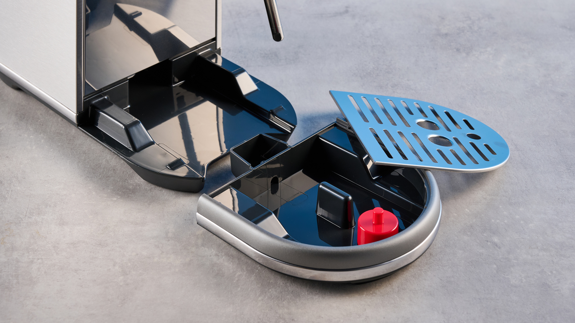 the breville bambino / sage bambino in silver photographed against a blue background with a wooden feature wall, showing the steam wand, group head, water tank, button controls, and espresso