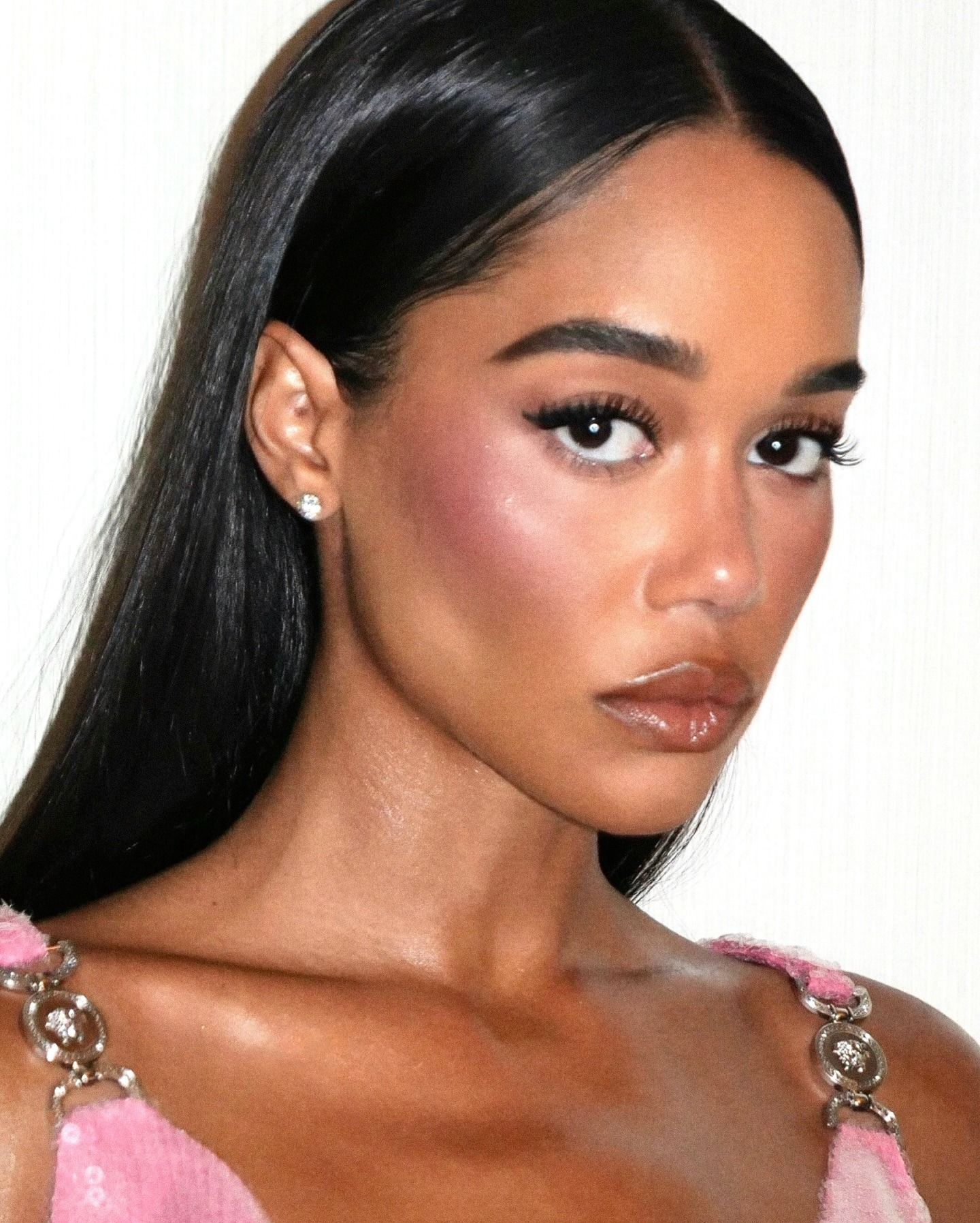 Laura Harrier wearing a pink dress and bright pink blusher on her cheeks