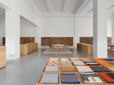 Colorful fabric samples are displayed in the foreground in custom wooden tables inside Maharam's new Gramercy showroom.