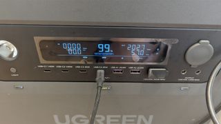 The front panel of the power roam power station with USB-C, USB-A and power inputs and outputs and a lit, blue LCD display illuminated