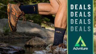 Darn Tough Merino socks being worn by hiker running across a river with deals logo