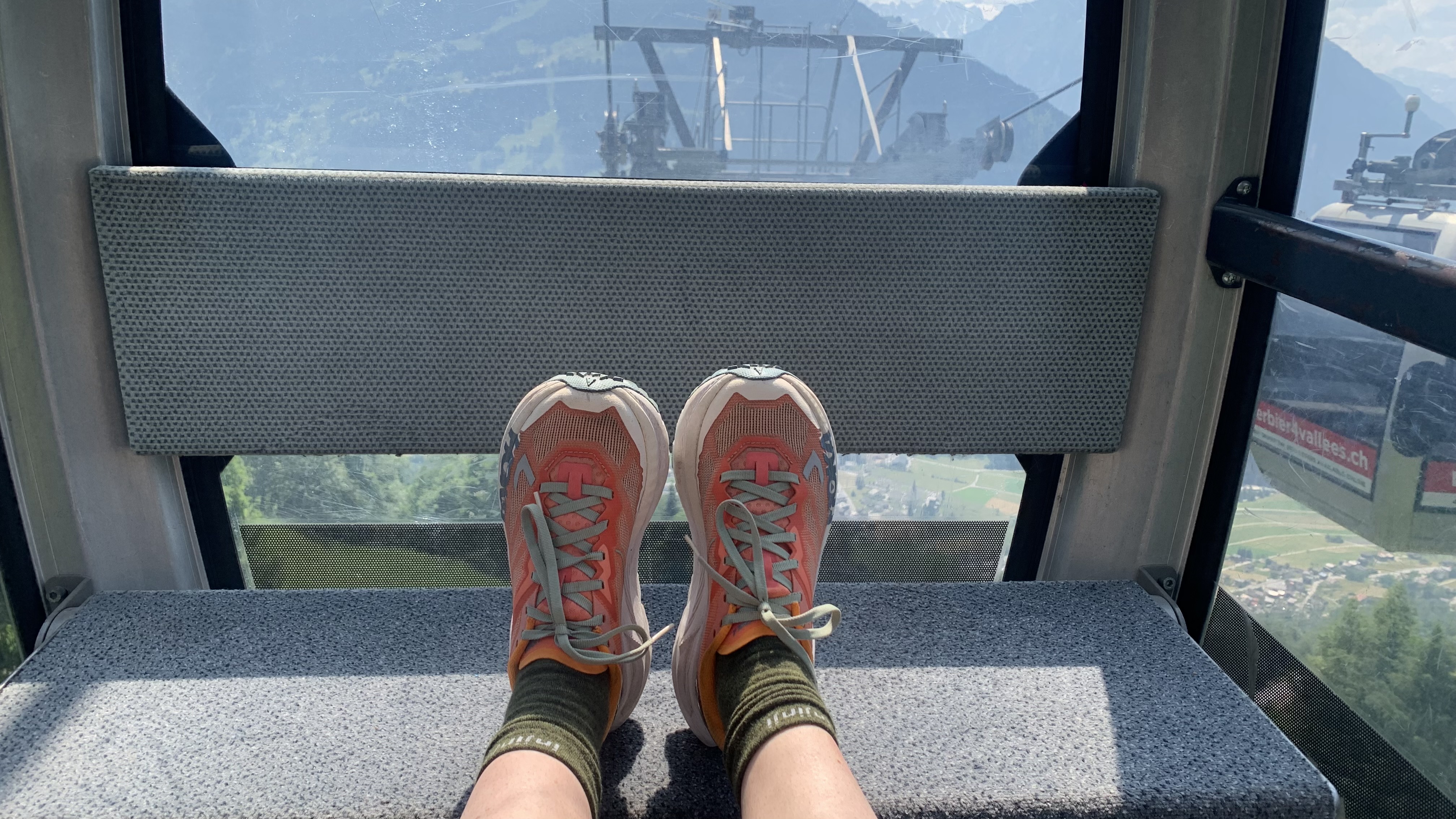 Runners feet up in ski gondola cabin wearing Hoka Mafate X trail running shoes