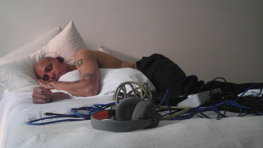 A producer wearing a pair of AIAIAI Tracks lying on a bed next to a pair of TMA-2 Wireless headphones