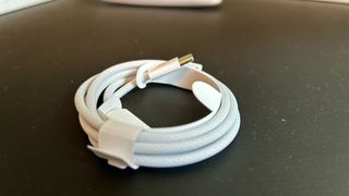 A white USB-C cable wrapped in a coil on a black leather surface