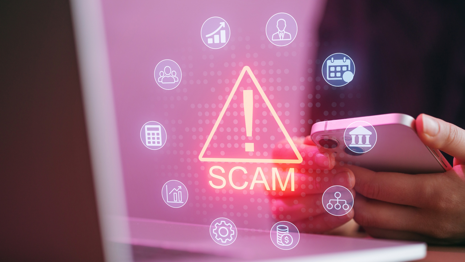 A person holds a smartphone with warning signs about scams visible. A laptop is nearby, showing icons related to finance and planning. The setting is bright and focused.
