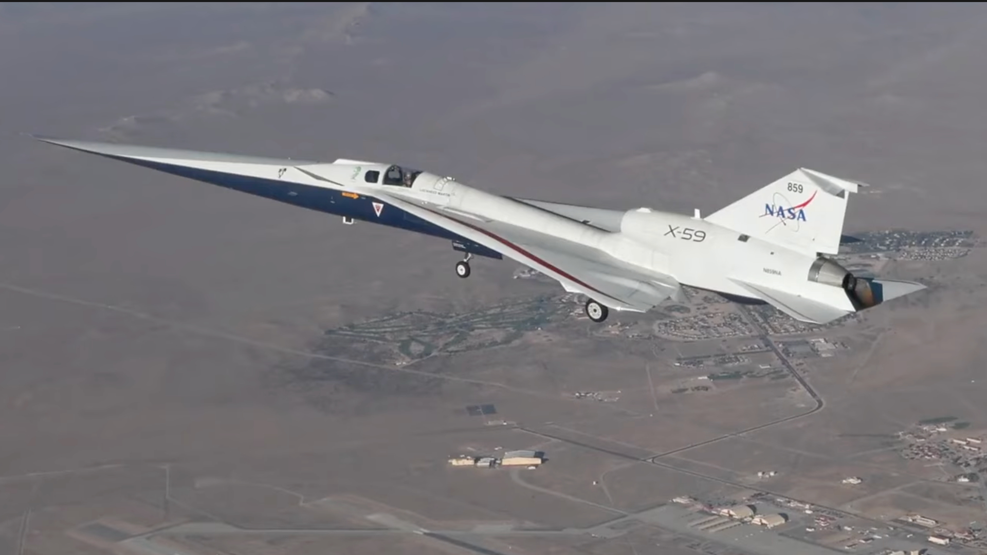 A small white plane flies above the desert
