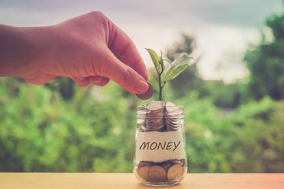 Cropped Hand Putting Money In Jar On Railing