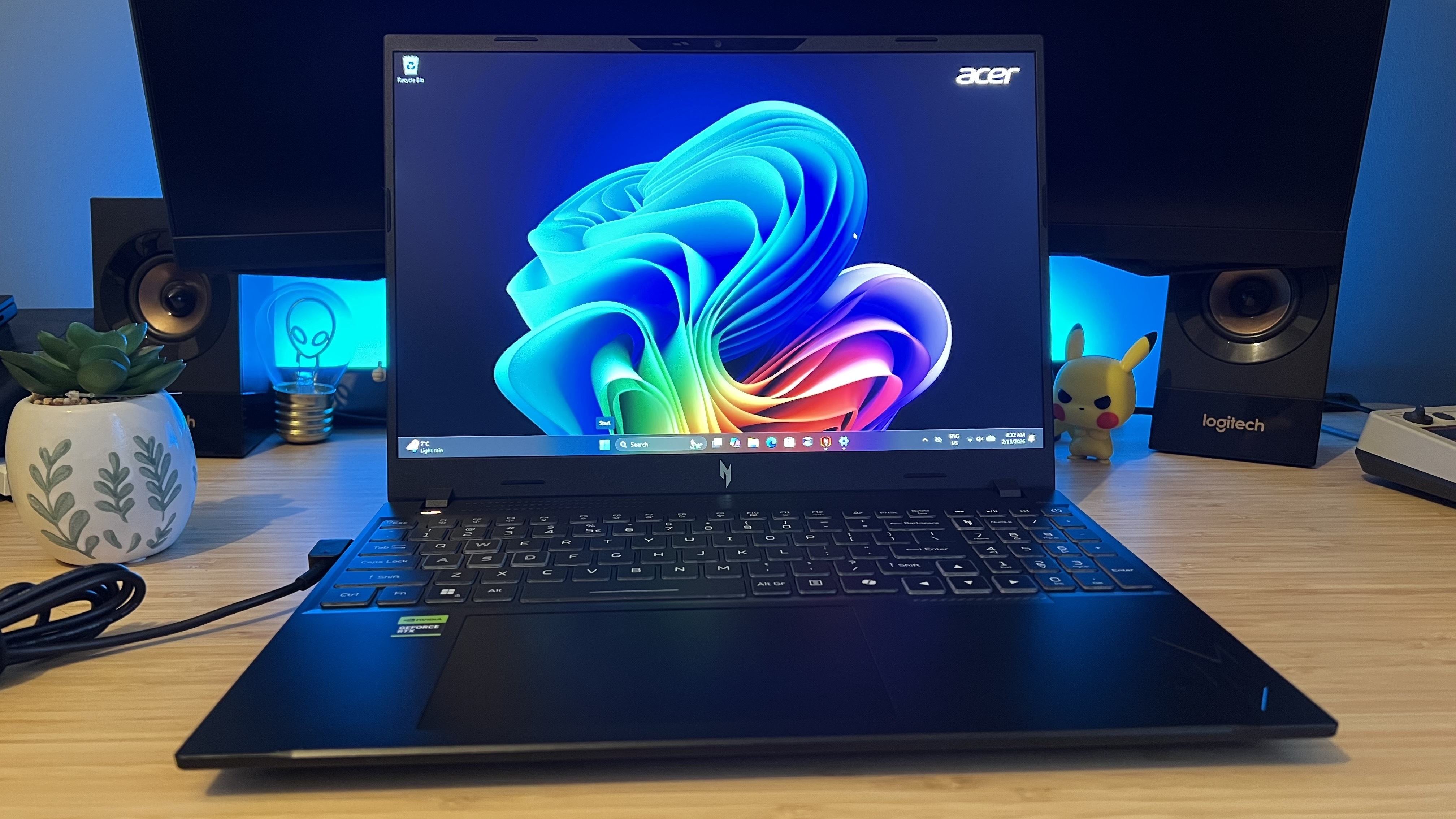 Acer Nitro V 16 AI gaming laptop on a wooden desk with blue backlighting
