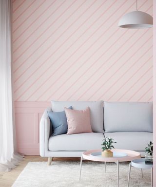 A pastel pink living room with a gray couch and white coffee table