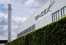 The outside of a SpaceX facility on a cloudy day with the SpaceX Falcon 9 rocket on display
