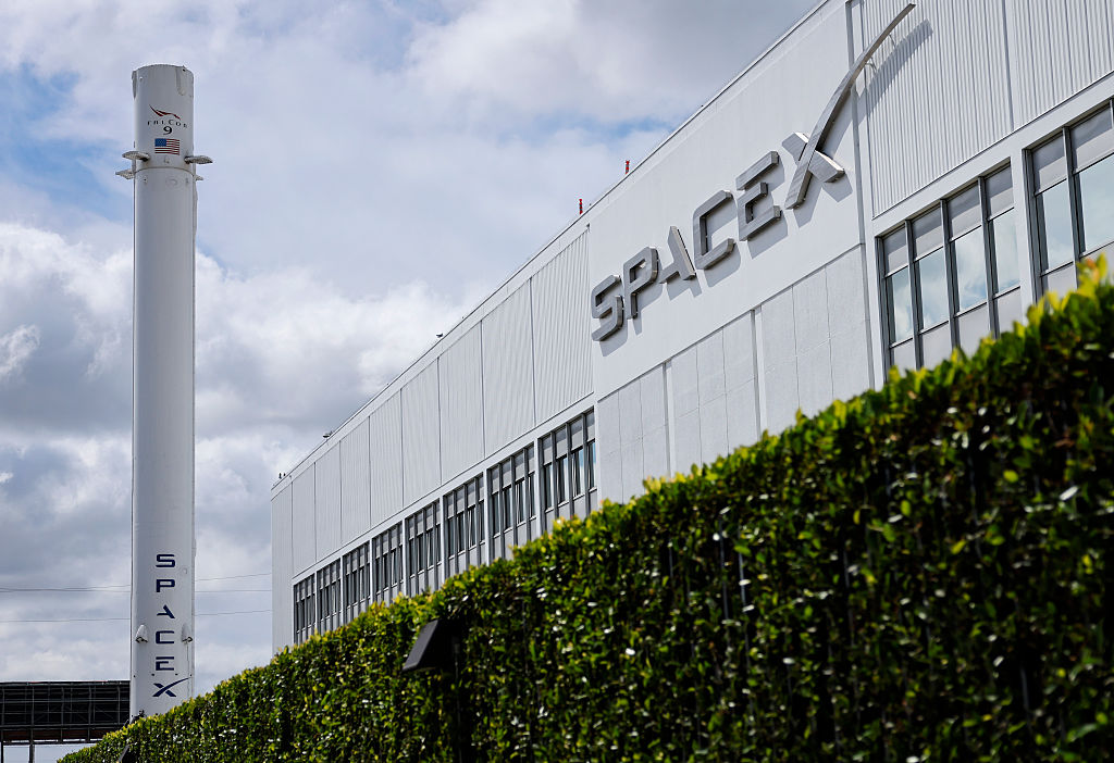 The outside of a SpaceX facility on a cloudy day with the SpaceX Falcon 9 rocket on display