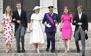 Queen Mathilde, King Philippe and their four children walking down a staircase in dress clothes